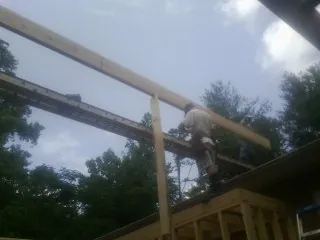 Carpenter setting a ridge beam over a new addition frame — Ice Dam Removal by Roofing Brothers in New Ross