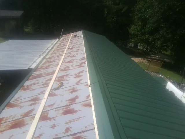 Old rusted panels beside newly installed green metal roofing — Wind Damage Roof Repair by Roofing Brothers in New Ross