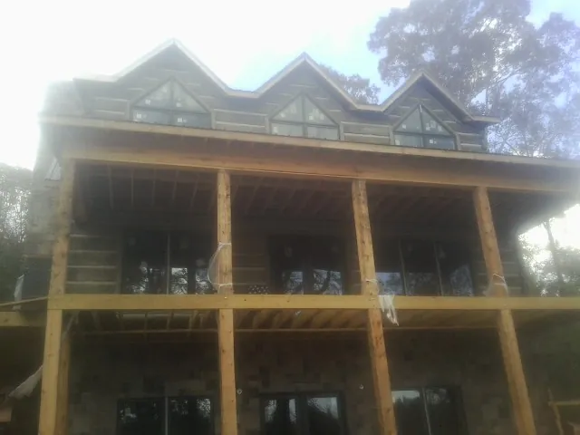 Dormers and porch framing on a large log home under construction — Roof Coating work by our crew in New Ross