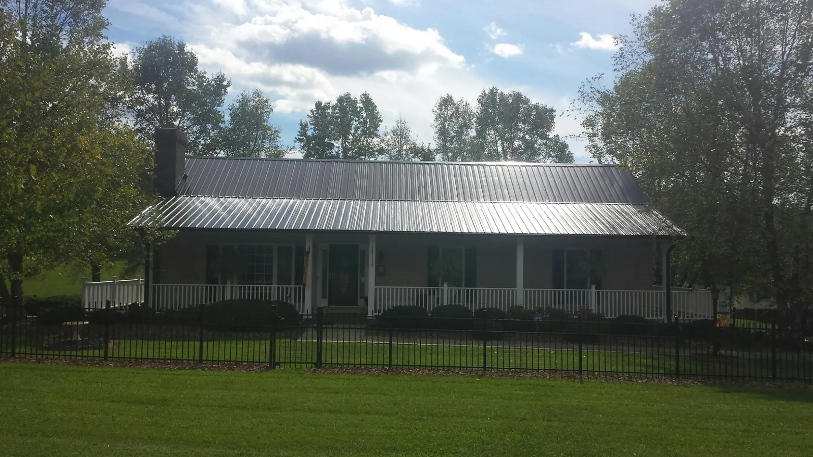 Gray metal roof on a brick ranch with a full width front porch — Gutter Guard Installation work by our crew in New Ross