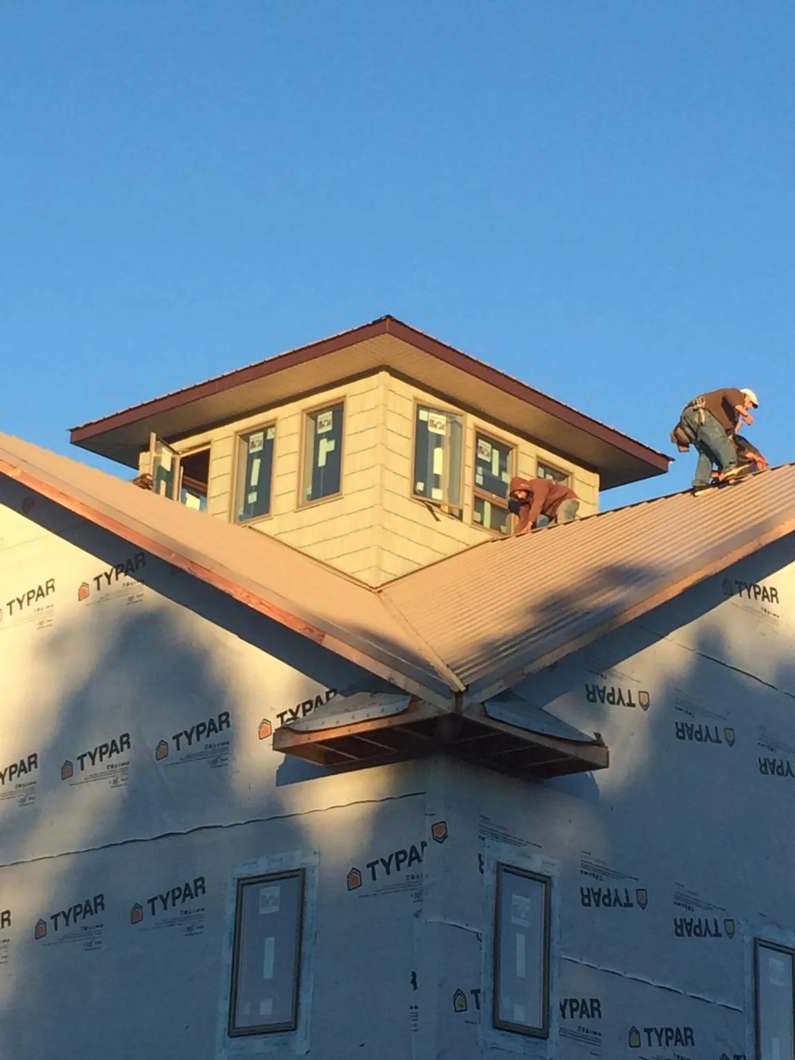 Roofers working around a rooftop cupola on a new metal roof at sunset — Roof Waterproofing in New Ross by Roofing Brothers